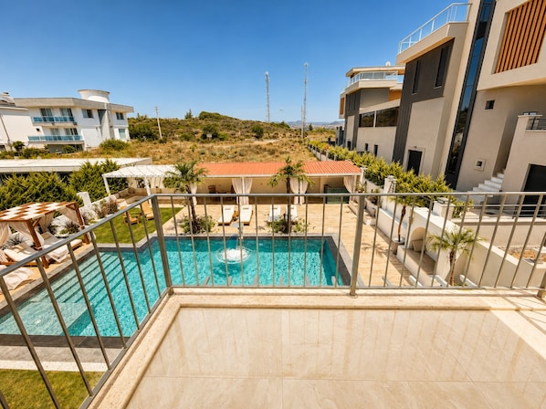 Un moderno edificio residencial con piscina, mobiliario exterior y vistas del paisaje circundante.