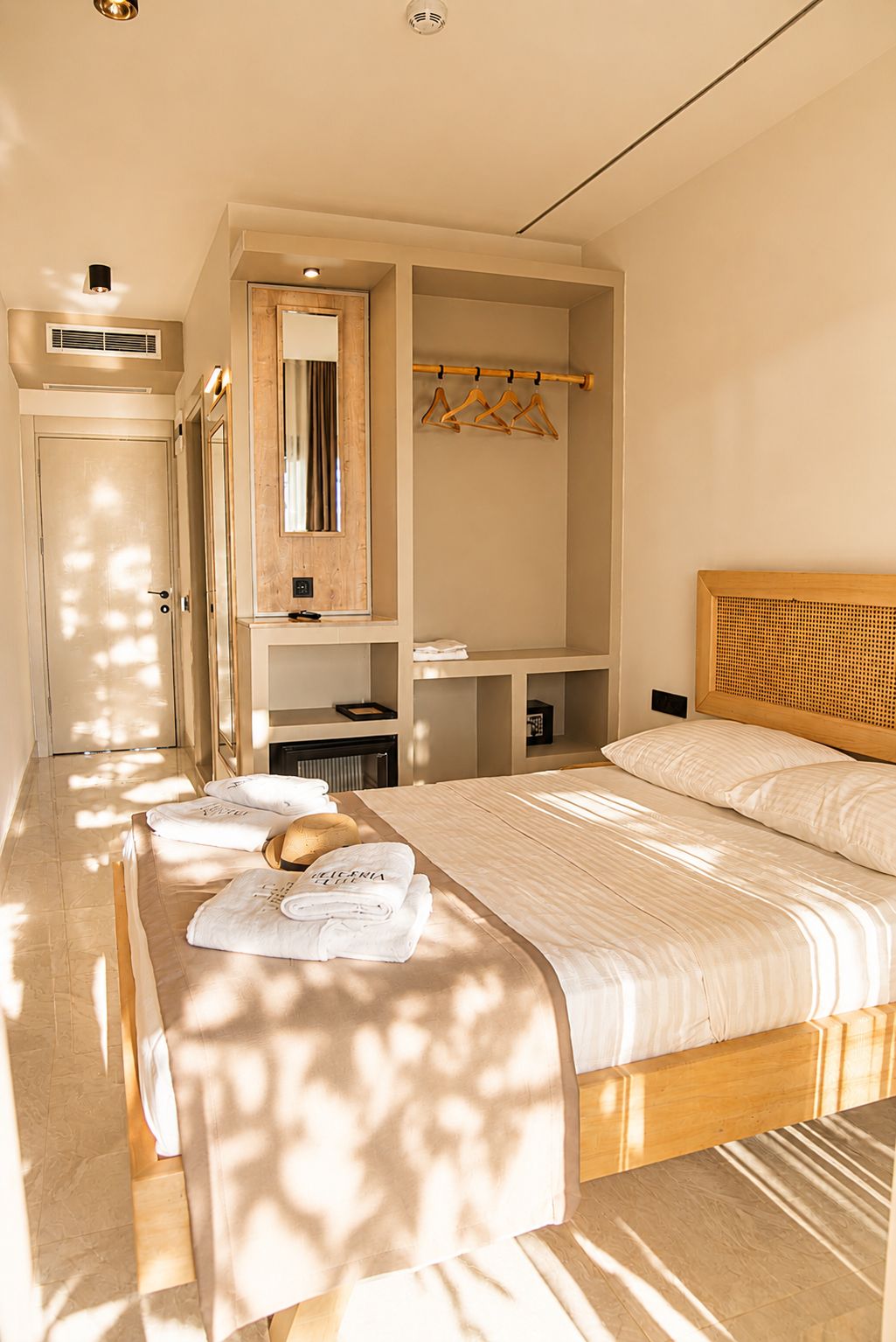Habitació d'hotel amb llit, tocador amb mirall, armari i zona de seients amb taula.