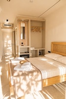 Une chambre d’hôtel comprenant un lit, une coiffeuse avec un miroir, une armoire et un coin salon avec une table.