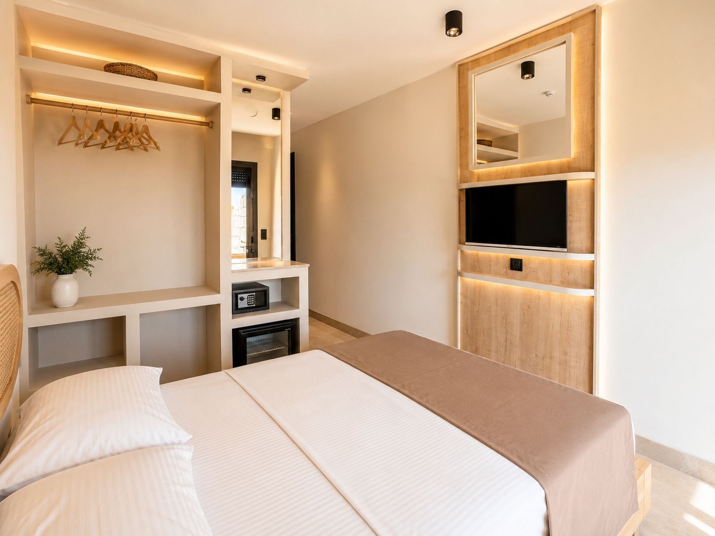 A modern bedroom with a bed, built-in TV, and a mirror.