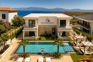 The Egéria Hotel with a pool, outdoor seating, and a view of the sea.