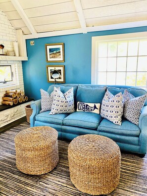 Ein blaues Sofa mit gemusterten Kissen, ein Willkommensschild und ein gerahmtes Bild an der Wand.