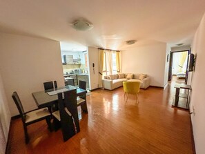 A living area with a sofa, a dining table with chairs, and a kitchen in the background. - Quito 2BR with Heated Pool & Gym Sleeps 4 Walk to Quicentro &  Estadio Atahualpa (Quito)