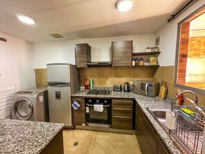 A compact kitchen with a built-in oven, microwave, and a stainless steel refrigerator. - Quito 2BR with Heated Pool & Gym Sleeps 4 Walk to Quicentro &  Estadio Atahualpa (Quito)