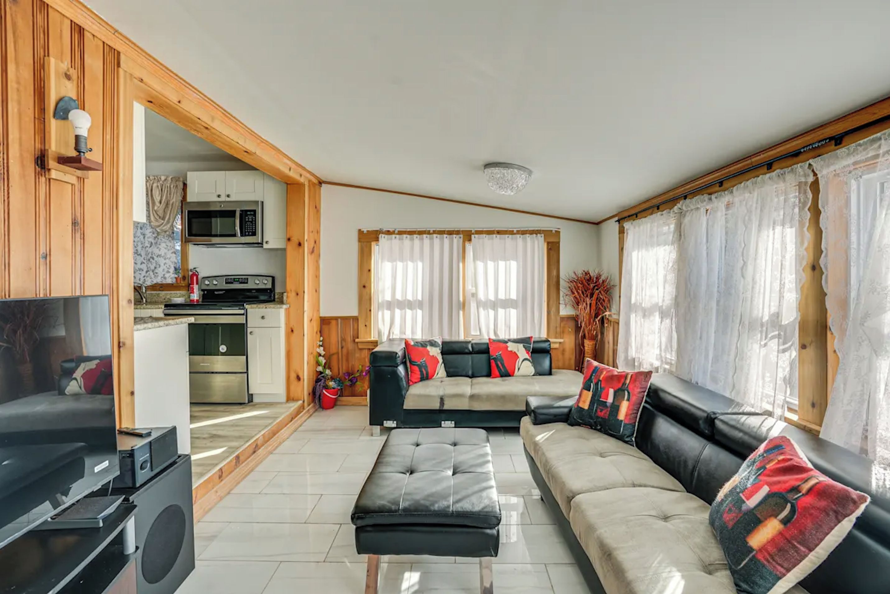 A modern living room with a sofa, ottoman, and a television.
