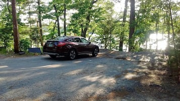A car parked on a gravel path in a wooded area.