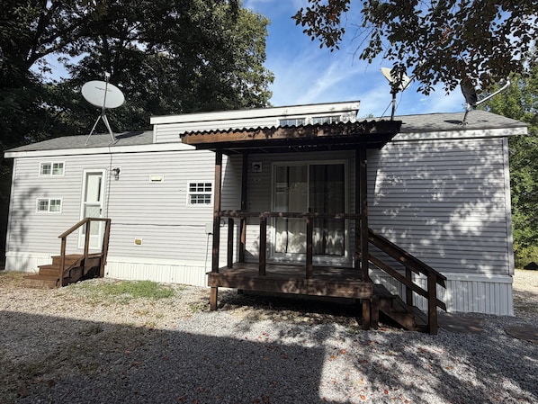 A small building with a porch, a satellite dish, and a wooden staircase.