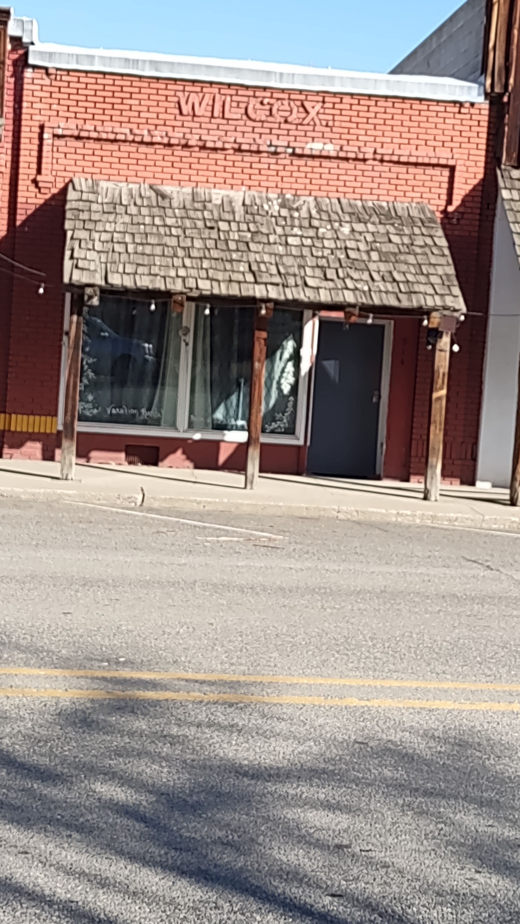 A red brick building with a covered outdoor seating area and large windows.