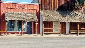 A street with a red brick building, a wooden structure with a sign, and a bench.