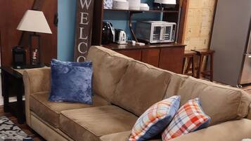 A living room with a beige sofa, patterned rug, and a 'WELCOME' sign.