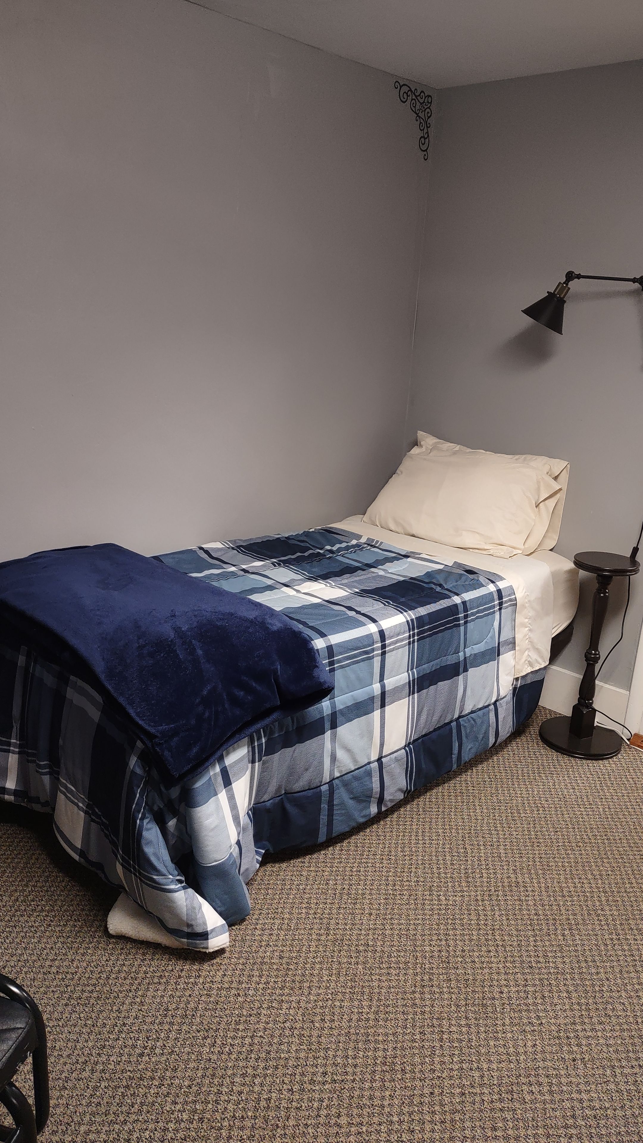 Ein Schlafzimmer mit Bett, Nachttisch, Lampe und Teppichboden.