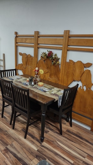Una mesa de comedor con cabecera de madera, dos sillas y camino de mesa.