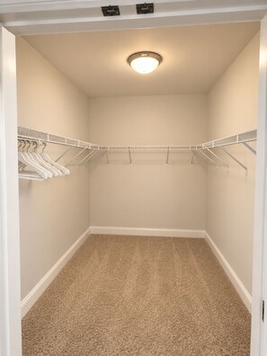 A walk-in closet with a beige carpet, white walls, and a ceiling light. - Luxury skyline living (Atlanta)