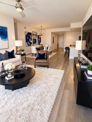 A modern living room with a round coffee table, a sofa, and a dining area with chairs. - Luxury skyline living (Atlanta)