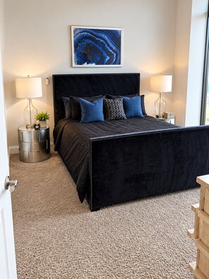Ein Schlafzimmer mit einem großen Bett, zwei Nachttischen, einem Wandbild und einem Teppichboden.