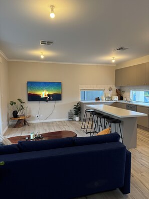 Ein modernes Wohnzimmer mit einem dunkelblauen Sofa, einem Holztisch und einem Gemälde einer Sternennacht.