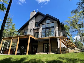 A two-story house with a balcony, large windows, and a stone chimney.