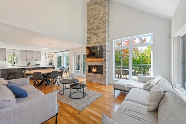 A spacious living area with a fireplace, a dining area, and a kitchen with a stone accent wall.