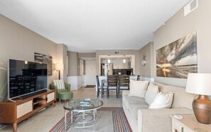 A modern living room with a flat-screen TV, a glass coffee table, and a sofa. - Nautilus Heights - St. Regis Condo #3110 (North Topsail Beach)