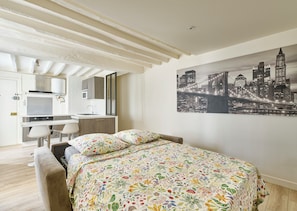 Ein modernes Schlafzimmer mit Bett, Stadtbild-Wandkunst, einer Küchenzeile und einem Badezimmer.