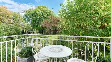Un balcon doté d’une balustrade en métal blanc, d’une table ronde et de deux chaises.