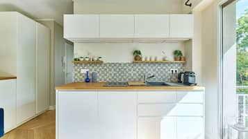 Une cuisine moderne avec des meubles blancs, un plan de travail en bois et un revêtement mural décoratif à motifs géométriques.