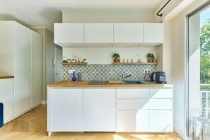 Une cuisine moderne avec des meubles blancs, un plan de travail en bois et un revêtement mural décoratif à motifs géométriques.