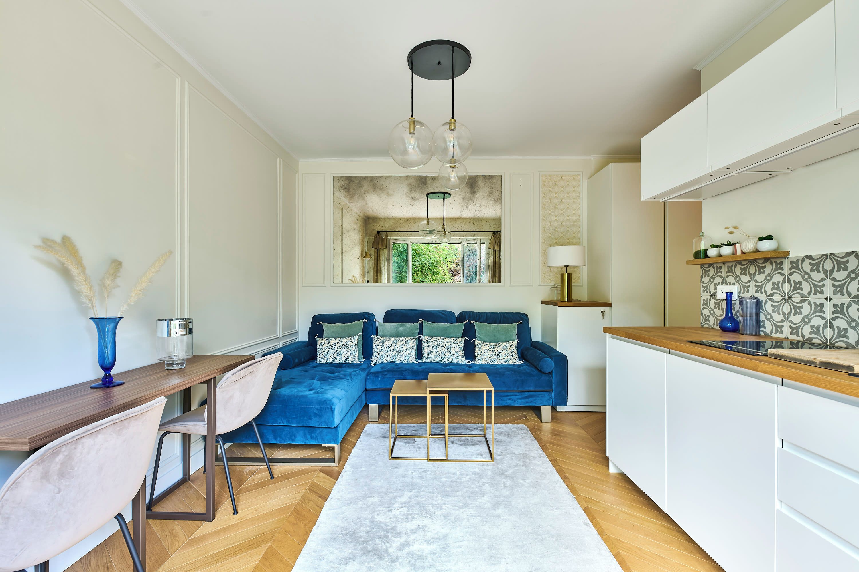 Une cuisine moderne avec un canapé bleu, une table à manger en bois et un îlot de cuisine.
