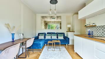 Une cuisine moderne avec un canapé bleu, une table à manger en bois et un îlot de cuisine.