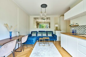 Une cuisine moderne avec un canapé bleu, une table à manger en bois et un îlot de cuisine.