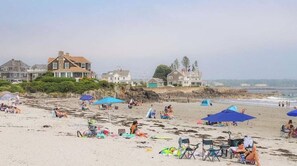 A beach with people, umbrellas, and houses in the background. - A Wave From It All with Hot tub (Kennebunk)