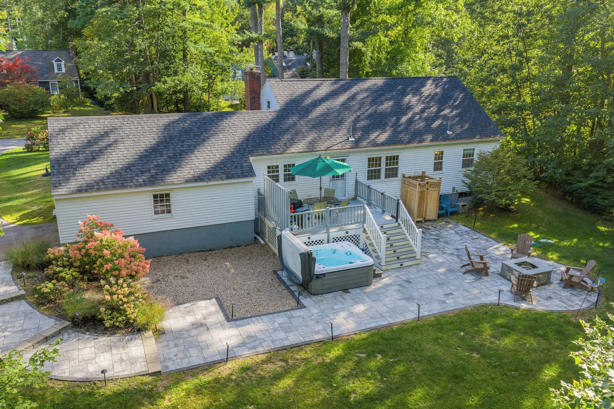 A two-story house with a patio, a hot tub, and outdoor seating.