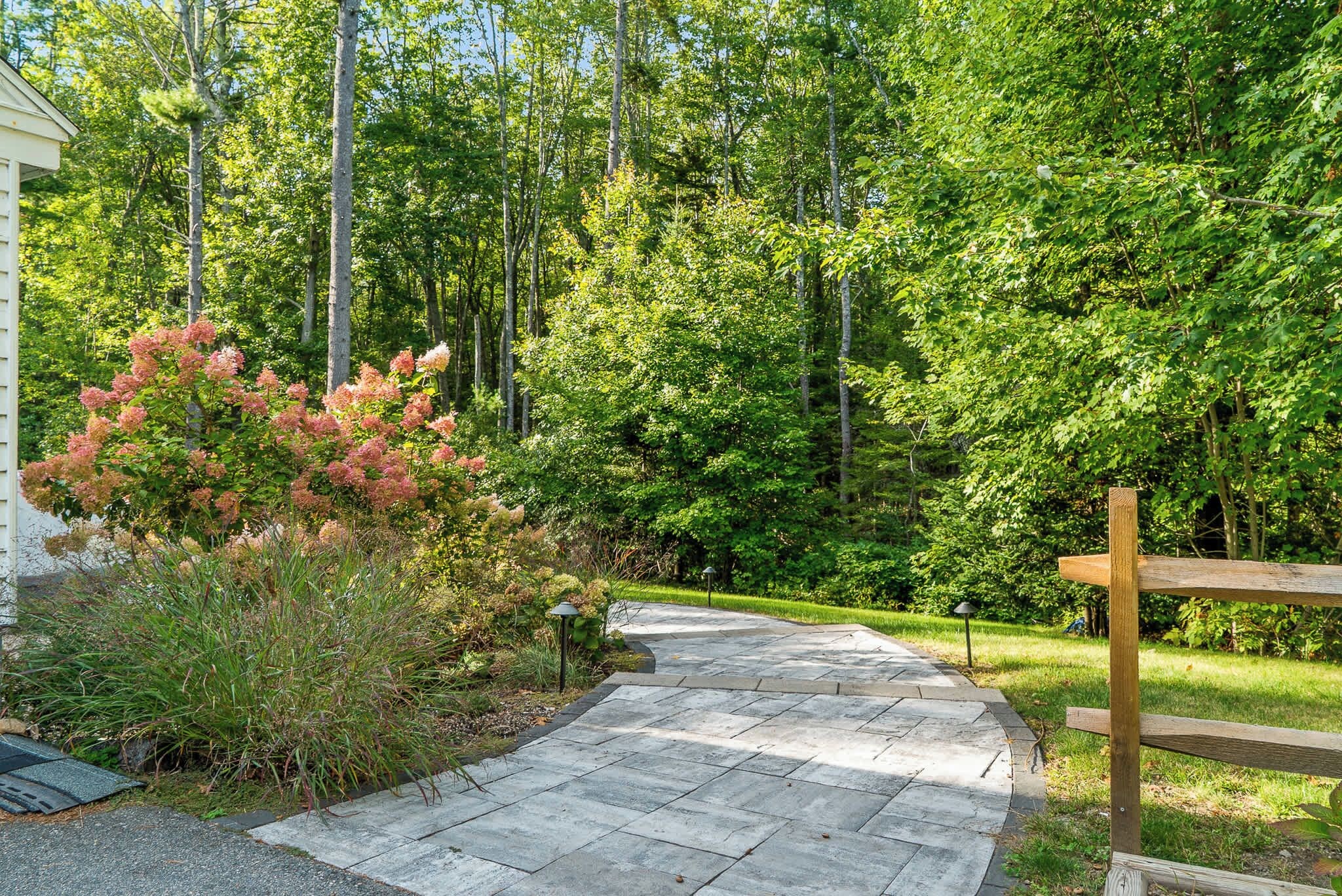 A stone pathway leading through a forested area with a wooden bench on the right.