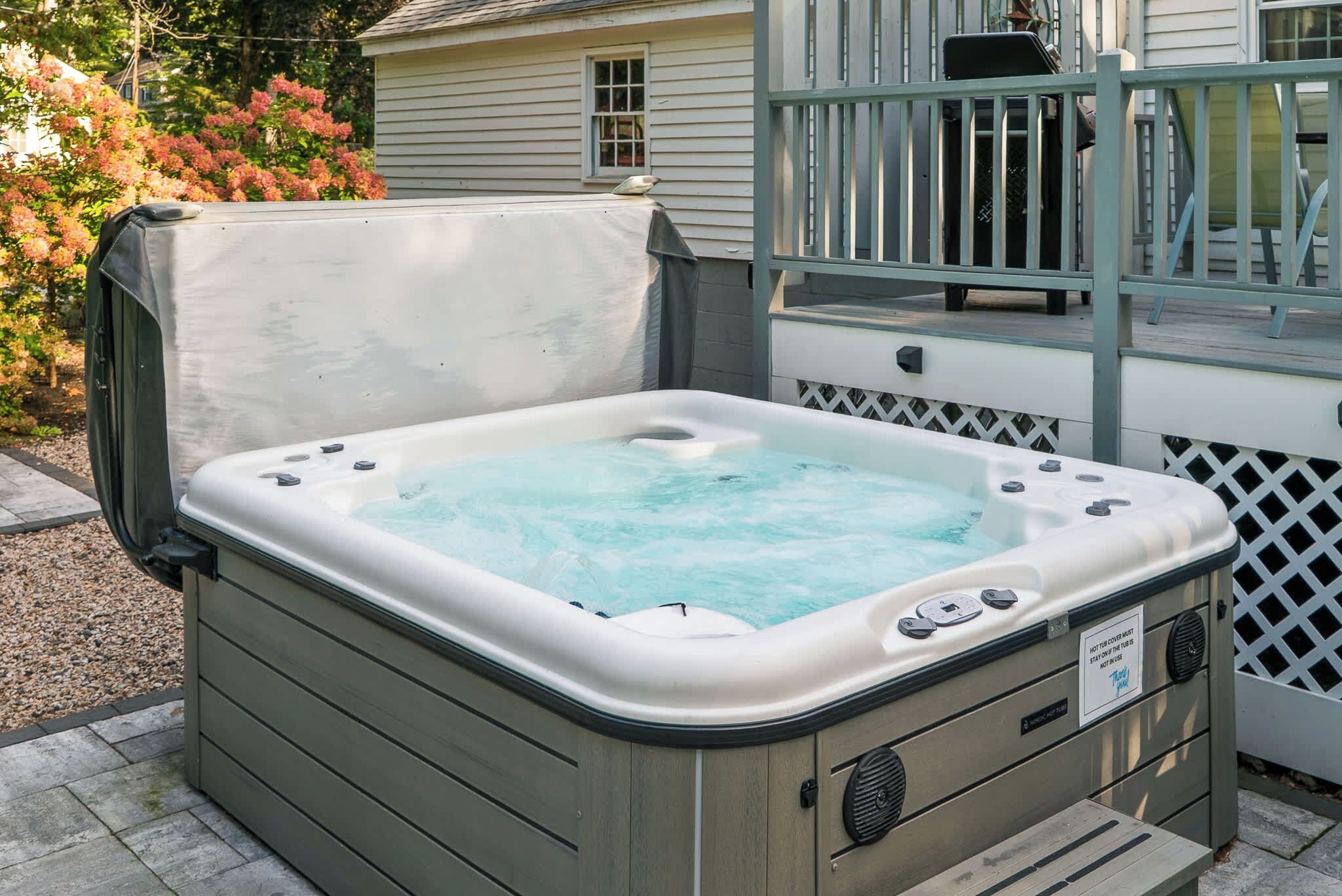 A hot tub with a cover, a control panel, and a warning label.