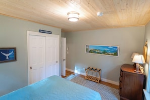 Une chambre à coucher avec un lit, une armoire, un tableau, une lampe et un ventilateur de plafond.