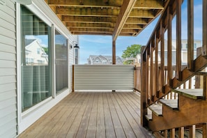 A wooden deck with a glass door and a view of neighboring houses. - Salty Breeze Condo with Pool (Wells)
