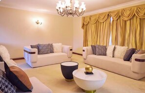 A living room with two sofas, a round coffee table, and a chandelier. - 5 BRD| sleeps 10| near airport|Perth CBD| Kings Park| mint (Dianella)