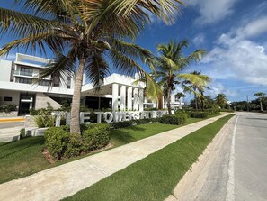 Un hôtel moderne doté d’une pelouse bien entretenue, de palmiers et offrant une vue sur un ciel dégagé.