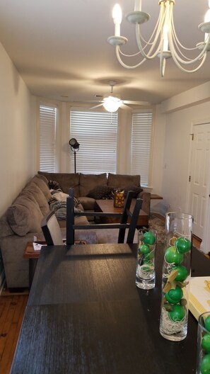 A living room with a dark wooden table, a sofa, and a chandelier. - Historic Greystone 2BR/2BA near Blue Line, Laundry (Chicago)