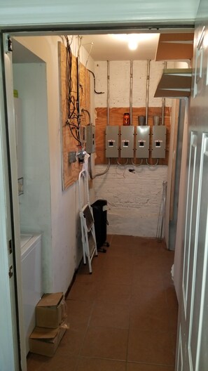 A utility room with exposed wiring, electrical panels, and a ladder. - Historic Greystone 2BR/2BA near Blue Line, Laundry (Chicago)