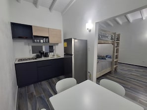 A compact kitchen with a refrigerator, stove, and sink, a bunk bed with a ladder, and a dining table with chairs. - 2 Walking to the beach (Noord)