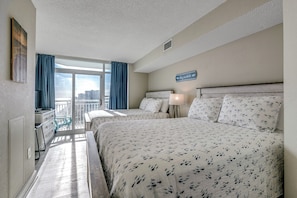 A hotel room with two beds, a balcony, a city view, and a sign on the wall. - Penthouse Paradise, Oceanfront Corner 2BD/2BA w/Panoramic Views, Prime location. (Myrtle Beach)