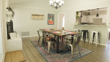 Un coin repas avec une table en bois, des chaises en métal, un tapis à motifs et un lustre.