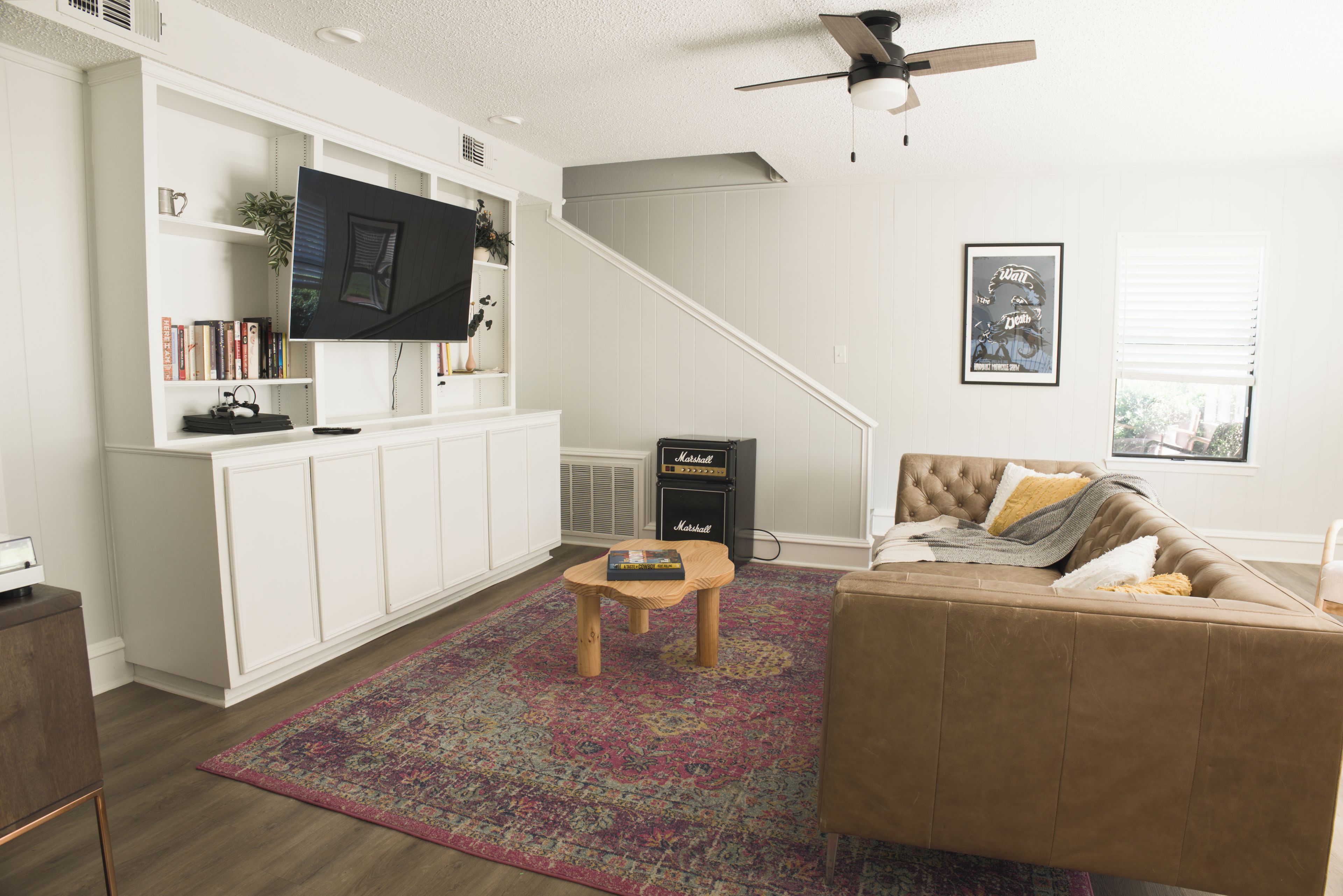 A living room with a television, bookshelves, a sofa, a coffee table, and a patterned rug.