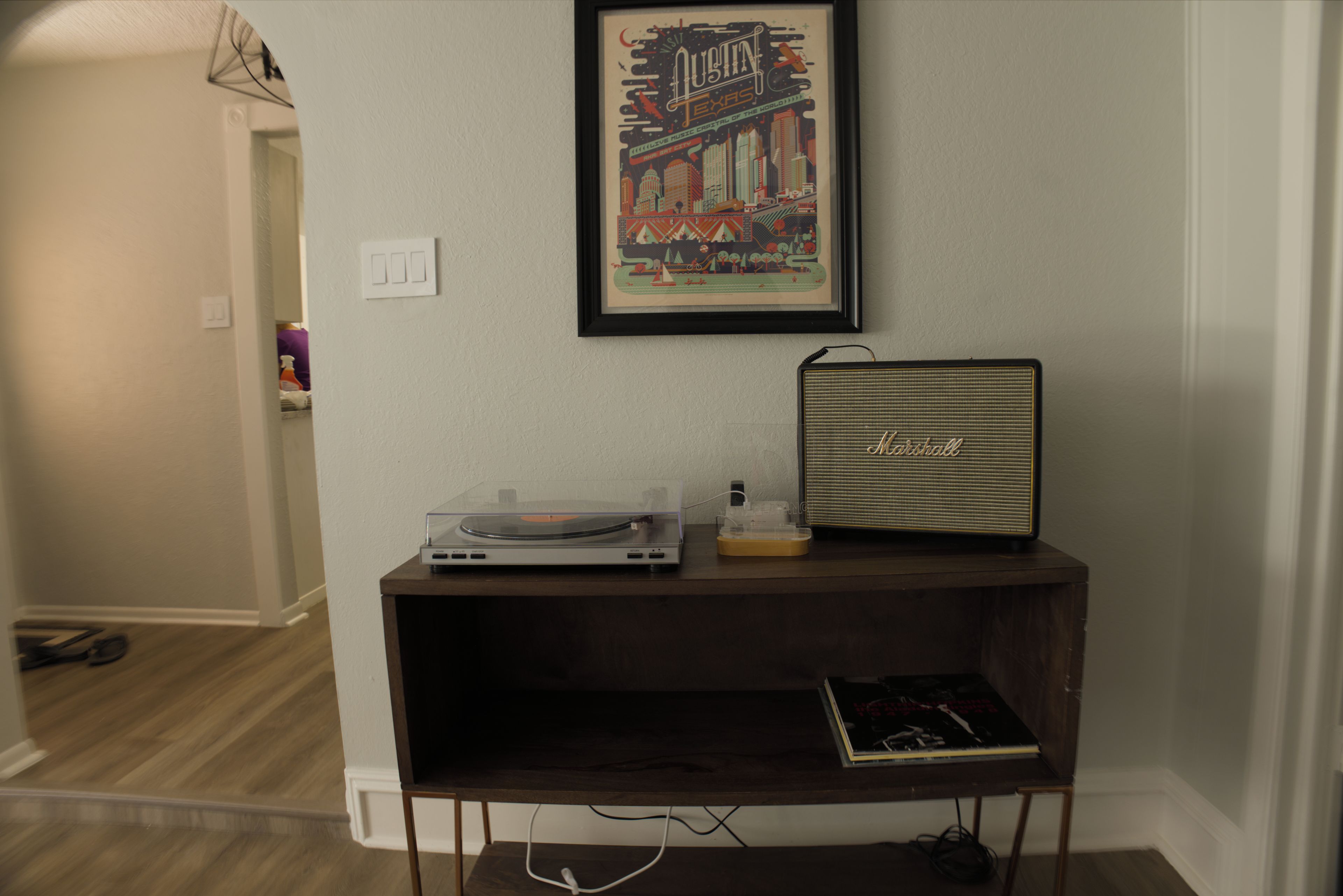 A room with a dark wooden entertainment unit, a framed poster on the wall, and a vintage radio.