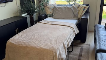 Una camera da letto con un letto, una televisione, un'ampia finestra e vista sull'esterno.