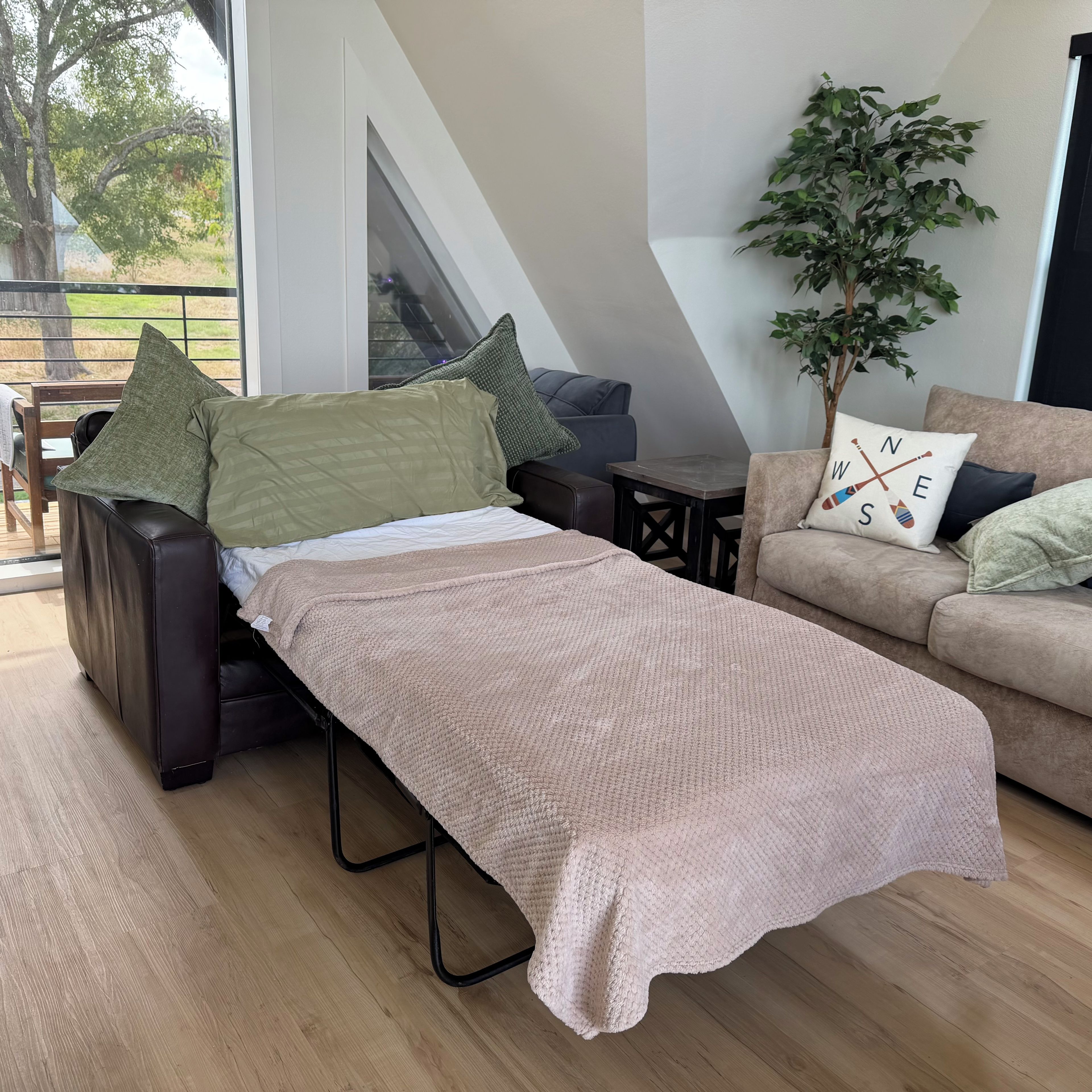 Un salon moderne comprenant un lit, un canapé, une table basse et une plante en pot.