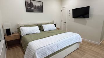 Un dormitorio con cama, mesita de noche, televisor montado en la pared y ventilador de techo.