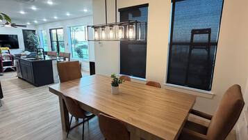 Un espace de salle à manger moderne avec une table en bois, des chaises et des luminaires suspendus.