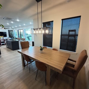 A modern dining area with a wooden table, chairs, and pendant lighting.